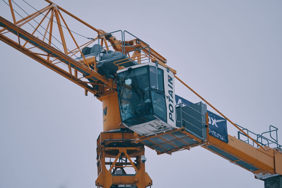 Doświadczony operator podnośnika precyzyjnie manewrujący koszem na placu budowy.