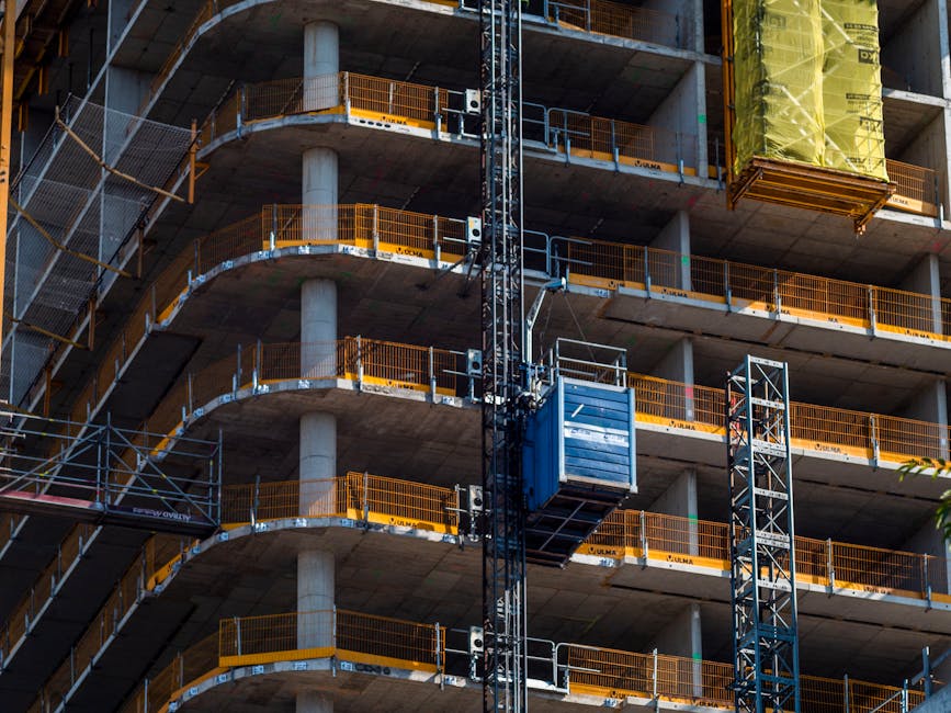 Podnośnik koszowy pracujący na nowoczesnym placu budowy w otoczeniu infrastruktury