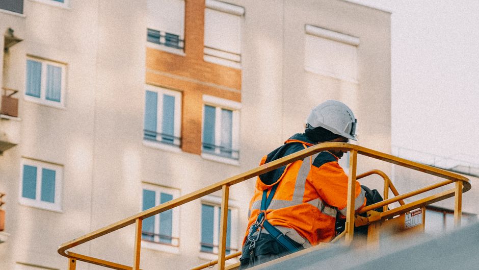 Pracownik budowlany z uprawnieniami UDT pewnie sterujący nowoczesnym podnośnikiem nożycowym na placu budowy