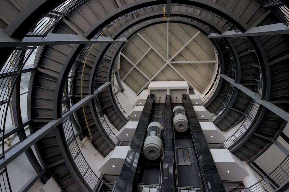 specjalistyczny podnośnik pająk pracujący w wąskim atrium nowoczesnego budynku