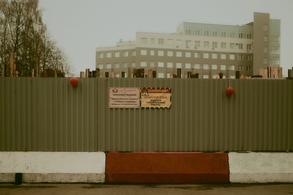 Ekipa budowlana wygradza strefę bezpieczeństwa wokół podnośnika koszowego za pomocą taśm ostrzegawczych i pachołków
